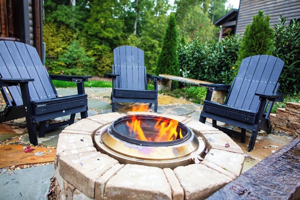 Pigeon Hills outdoor fire pit with Adirondack chairs stone patio and mountain landscaping